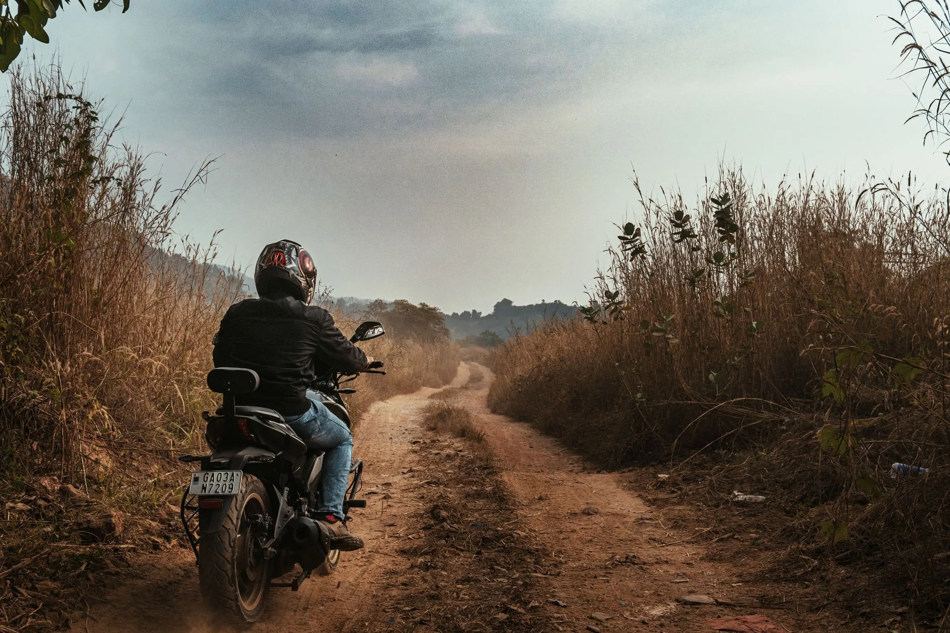 Rugged terrain with parked BMW 1200 GS adventure motorcycle, muted colors, soft lighting.