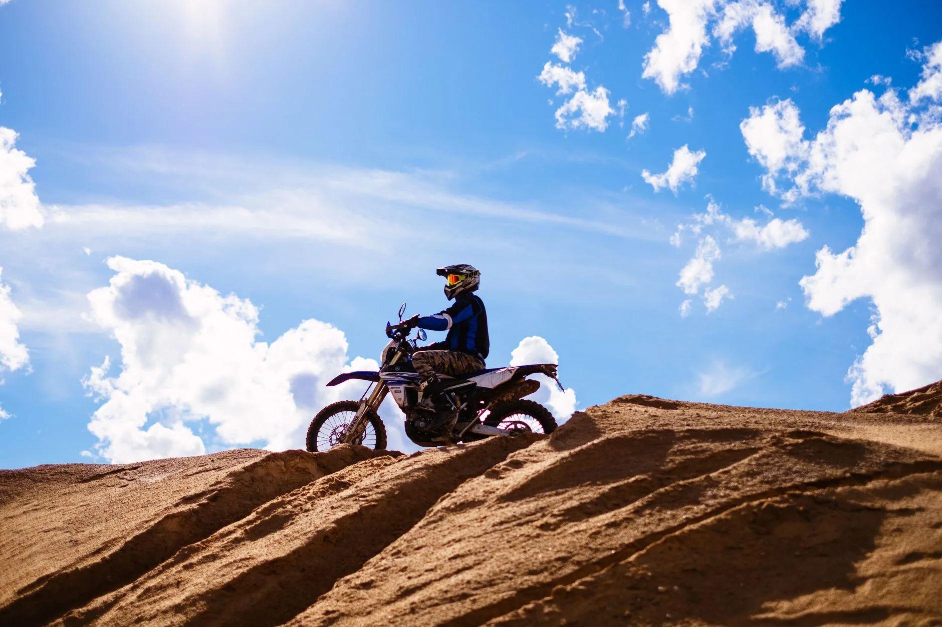 A confident woman in motorcycle gear stands beside her bike, ready to ride.