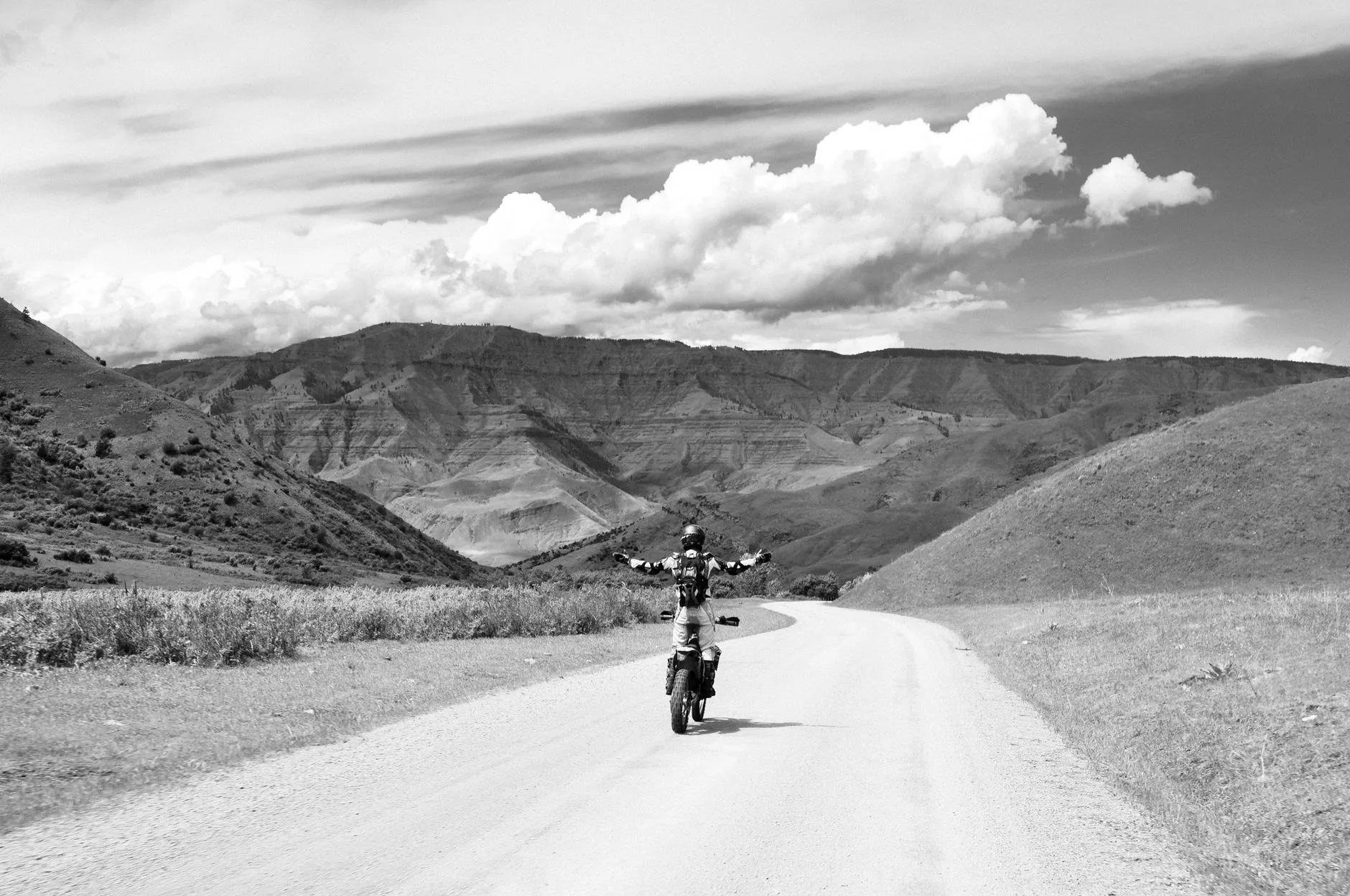 Rugged, worn Draggin Jeans draped over a motorcycle saddle, muted colors, soft lighting.